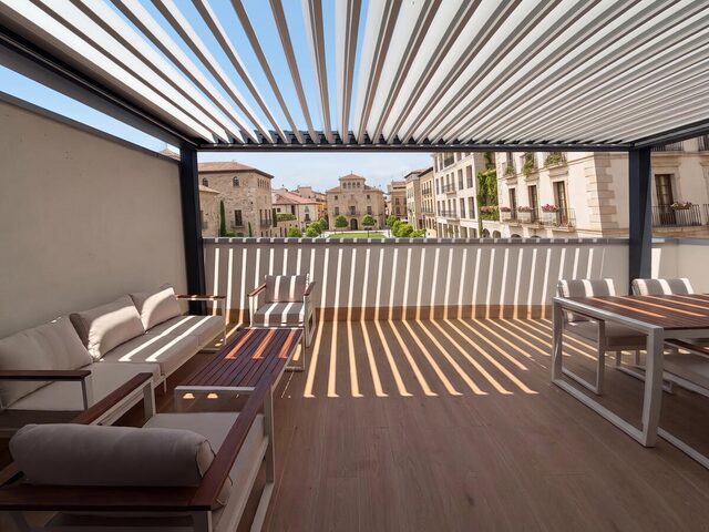 Pérgola bioclimática CERCA en la terraza de un ático, con vistas a la ciudad, a mediodía
