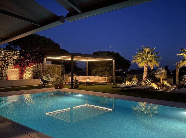 Pérgola bioclimática CERCA autoportante en un jardín junto a la piscina, de noche, con la iluminación LED encendida