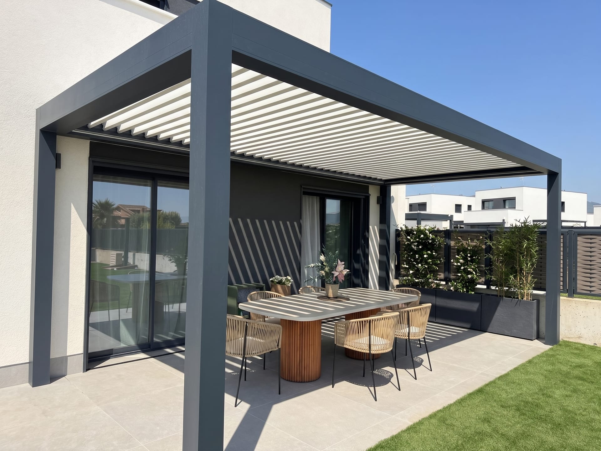 Pérgola bioclimática CERCA adosada a una vivienda, sobre una terraza con mesa de comedor y jardín